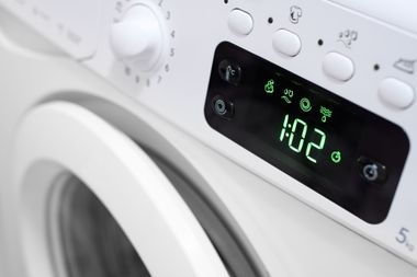 Front panel of a white washing machine displaying 1:02 on a green digital screen.