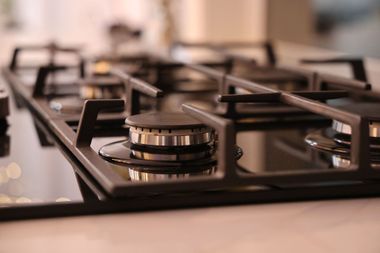 Close-up of a black gas stovetop with control knobs in a kitchen