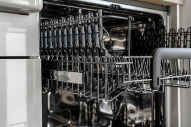 Open dishwasher rack filled with clean dishes and glassware ready to unload