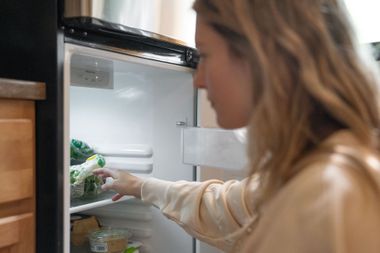 Woman reaching into an open refrigerator in a kitchen