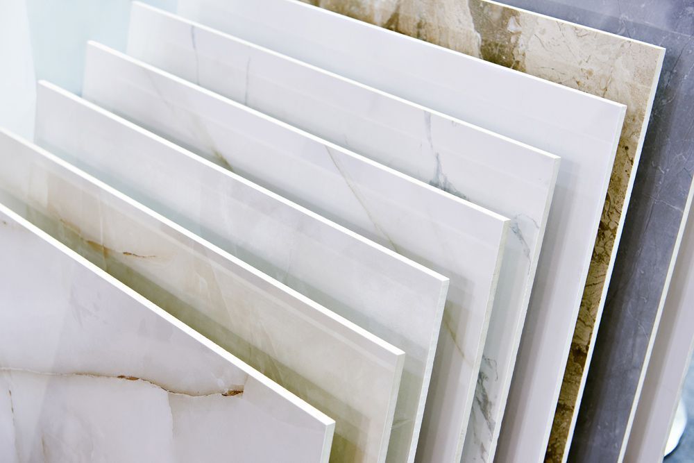 Stacked White and Beige Marble Tiles Leaning Upright, Showing Polished Stone Surfaces — Mid Coast Tile Co in Taree, NSW