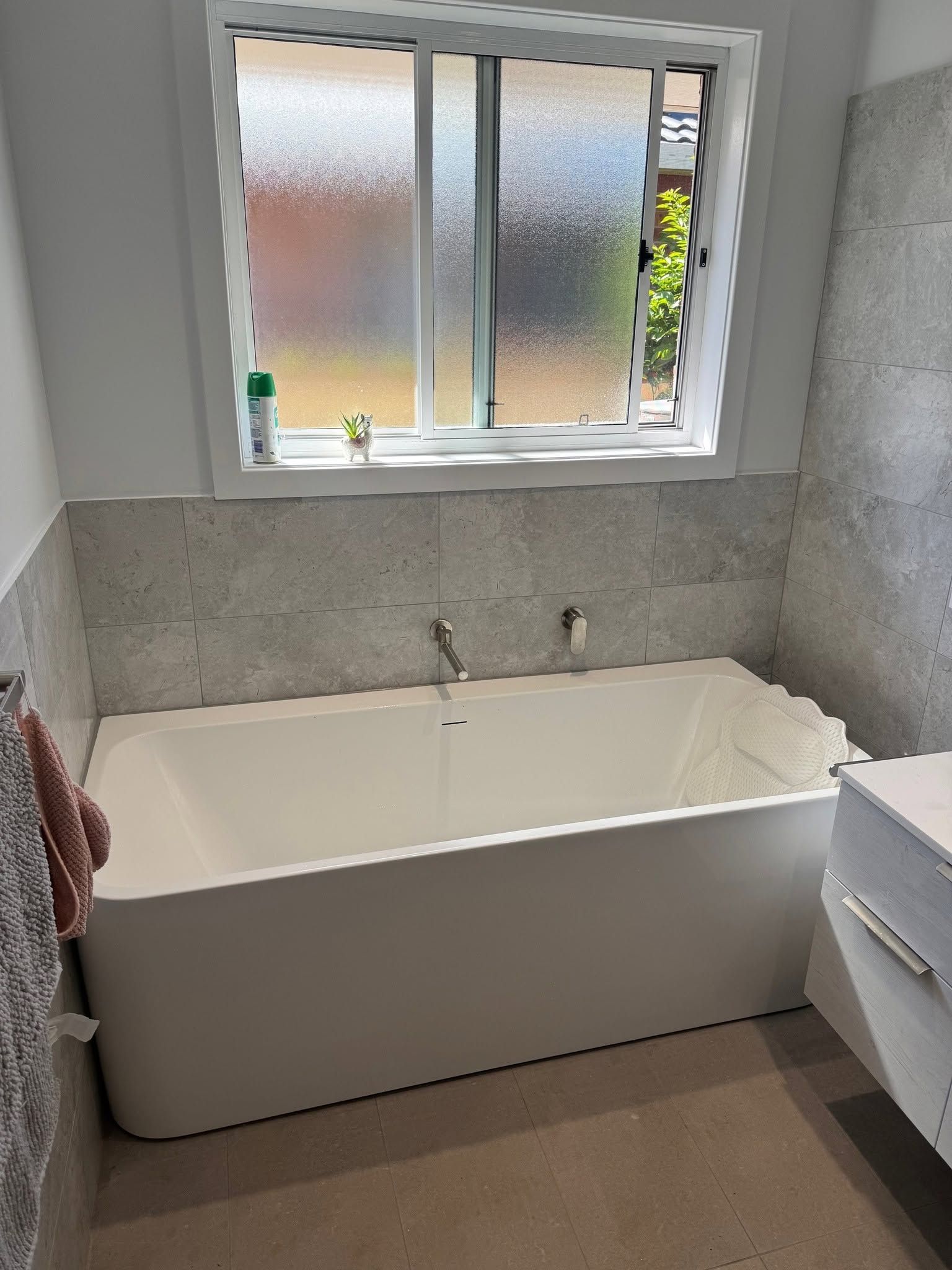 Small Bathroom with A White Bathtub Under a Frosted Window — Mid Coast Tile Co in Wingham, NSW