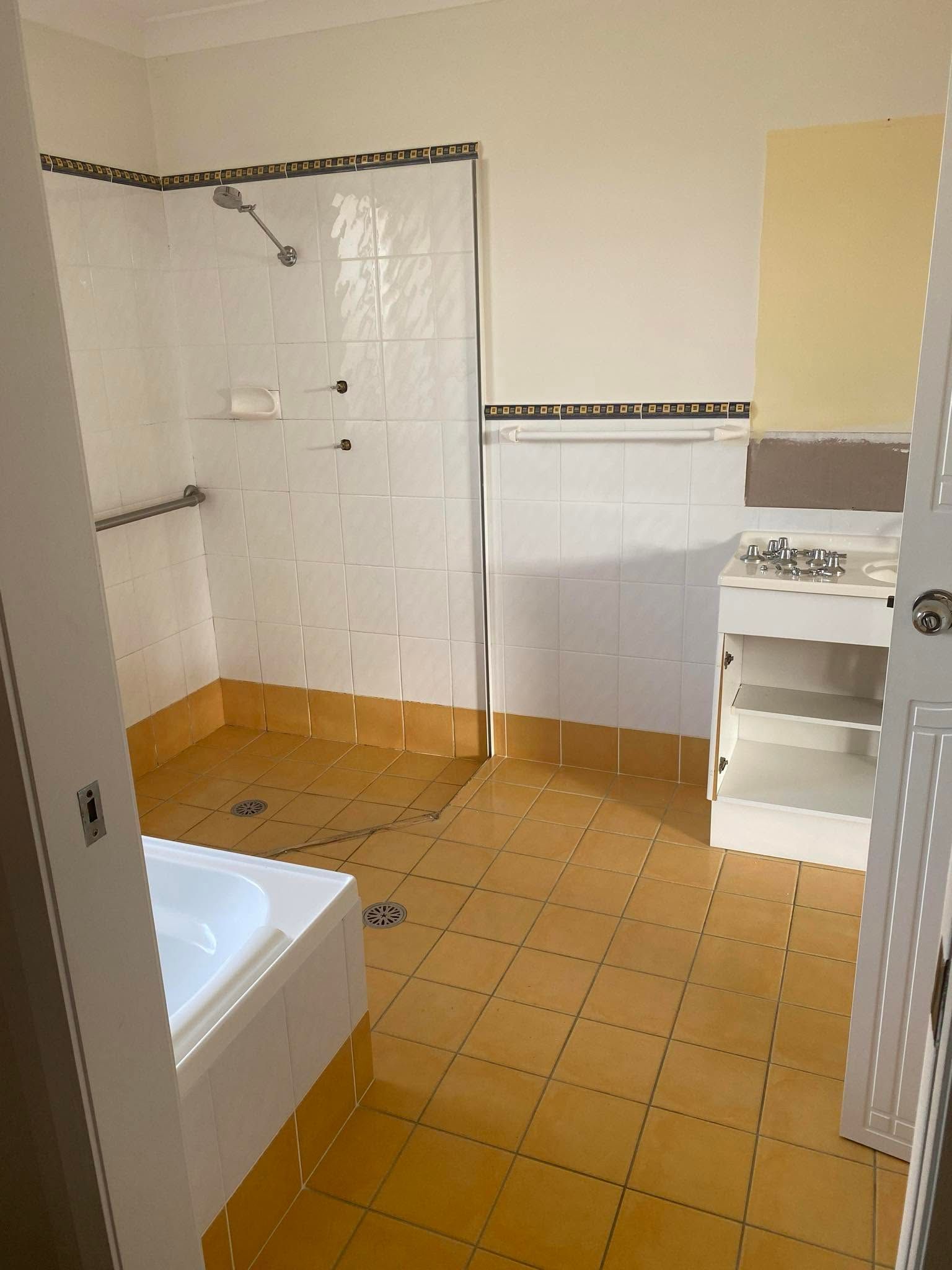 Small Bathroom with Yellow Tiled Floor, White Tub, Sink — Mid Coast Tile Co in Forster, NSW