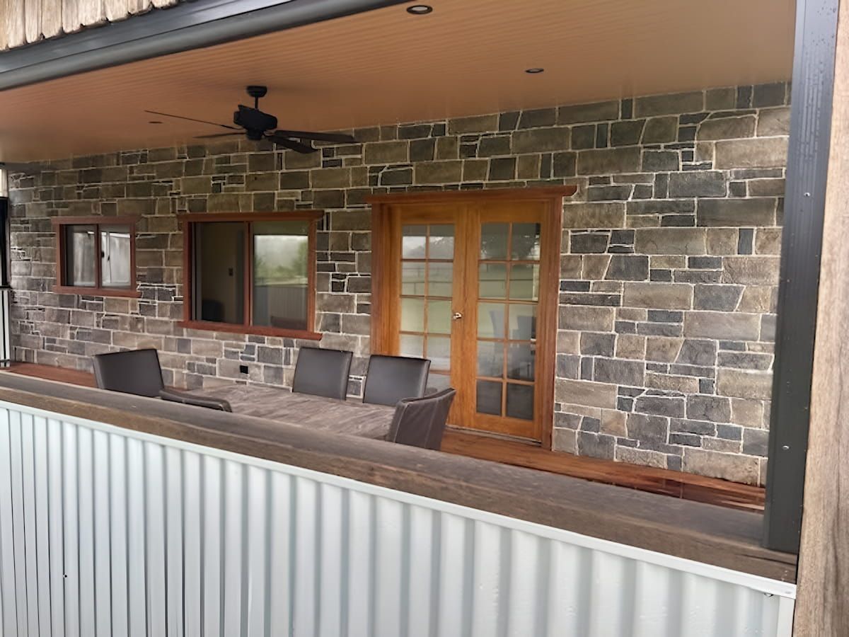 Covered Porch With Stone Wall, Wooden Doors, and Outdoor Table and Chairs — Mid Coast Tile Co in Taree, NSW