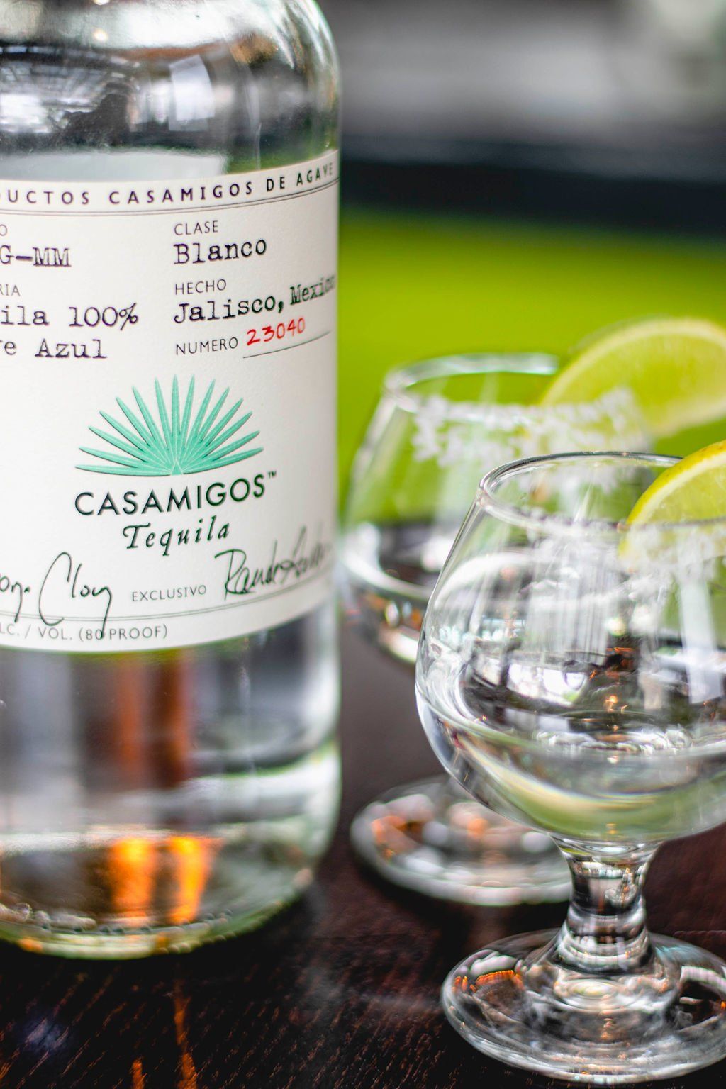 A bottle of casamigos tequila is sitting on a table next to two glasses of tequila.