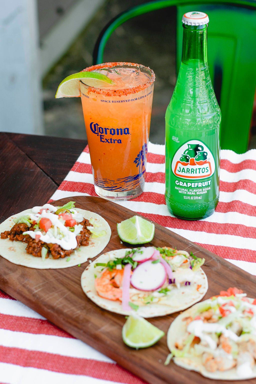 A wooden cutting board topped with tacos and a drink.