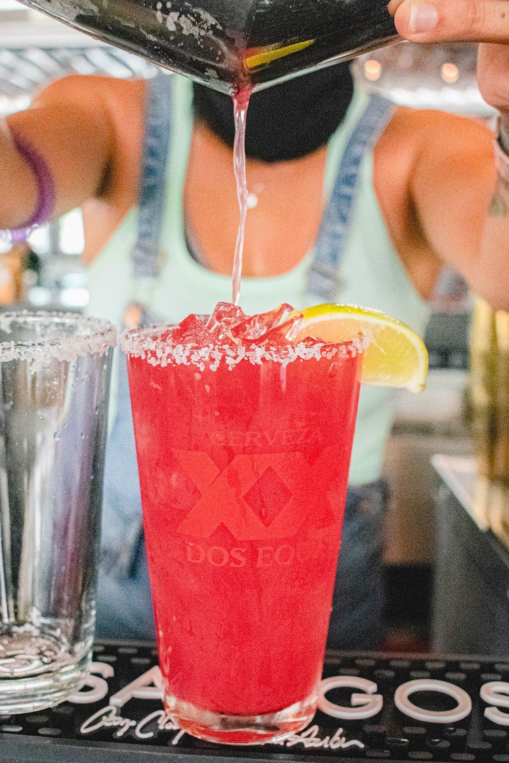 A bartender is pouring a red drink into a glass.