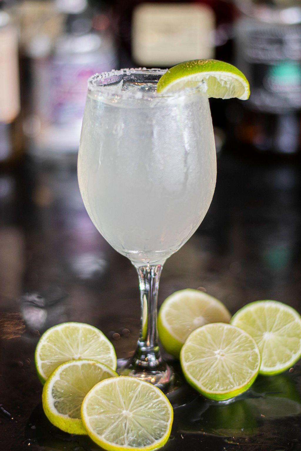 A margarita in a wine glass with a slice of lime on top.