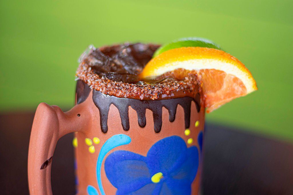 A cocktail mug with a slice of orange on top of it.