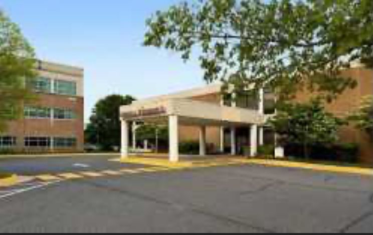 Hospital entrance with a covered walkway and a two-story building.