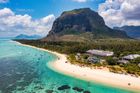 Turquoise lagoon and white sand beach beside a lush green mountain under a bright blue sky