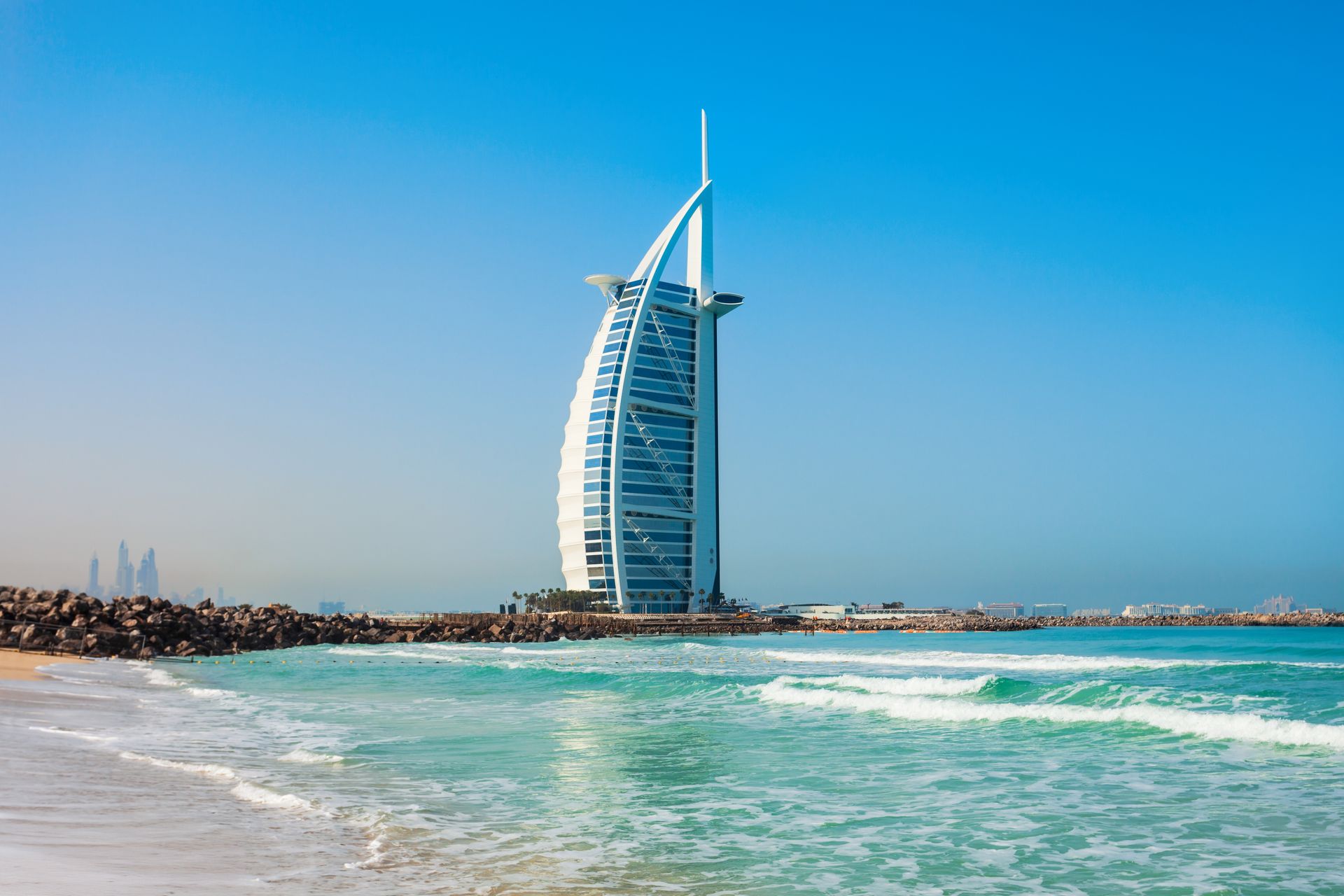 Burj Al Arab hotel on a sunny beach with turquoise water and a clear blue sky
