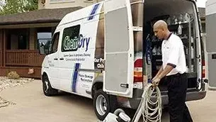 A man is pushing a vacuum cleaner in front of a century van.