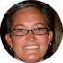 A woman wearing glasses and earrings is smiling in a circle.