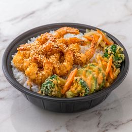 Panda Express-style bowl with orange chicken, white rice, and mixed vegetables in a black takeout container