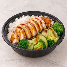 Chicken rice bowl with glazed sliced chicken, broccoli, zucchini, and cabbage in a black container