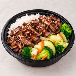 Grilled beef over rice with broccoli and mixed vegetables in a black bowl