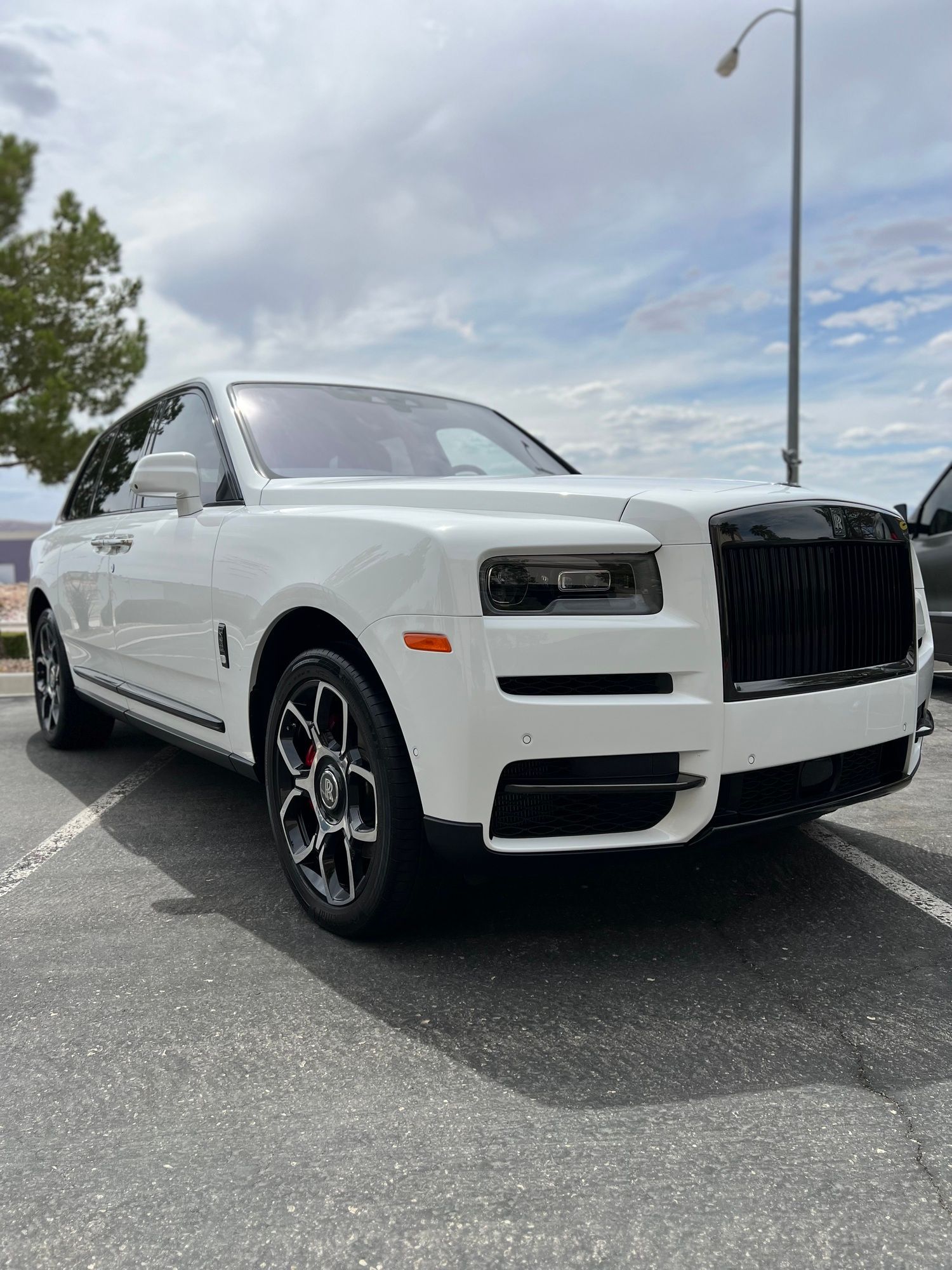 A white rolls royce cullinan is parked in a parking lot.