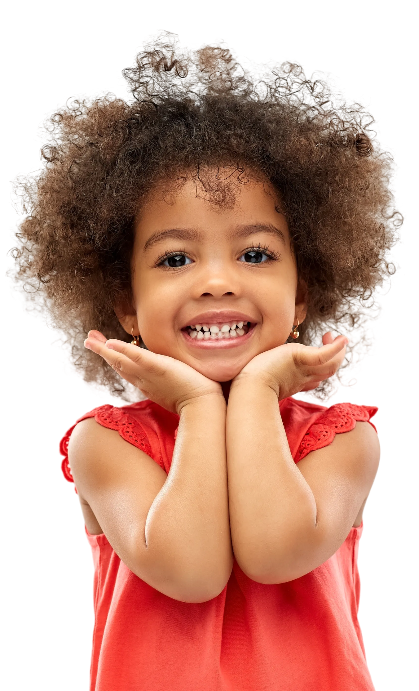 A smiling child with curly hair wearing a red top, posing with hands cupped under their chin against a white background.