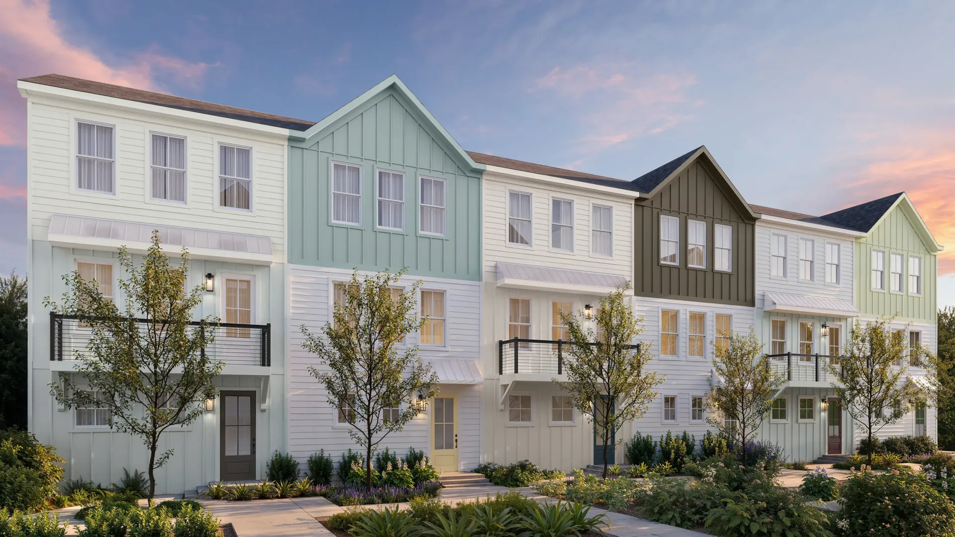 Row of pastel modern townhouses with trees and gardens under a pink evening sky