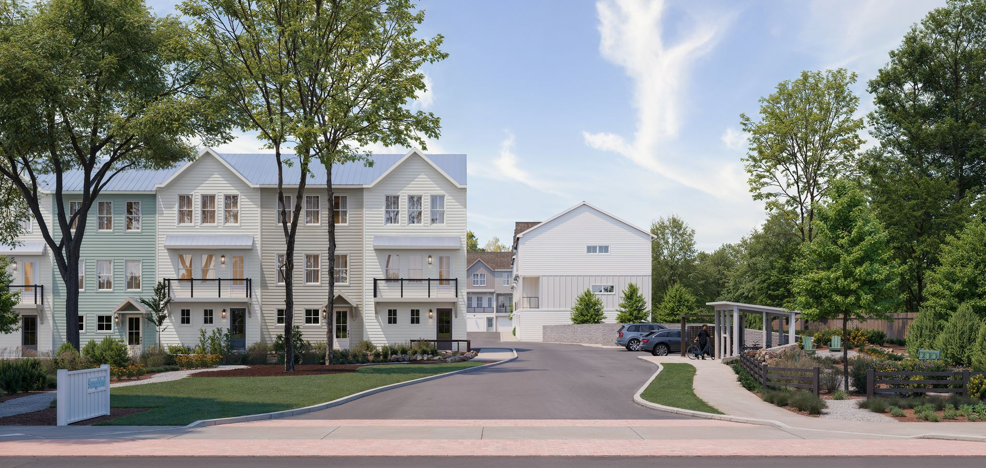 White townhomes beside a curved driveway and trees on a sunny day