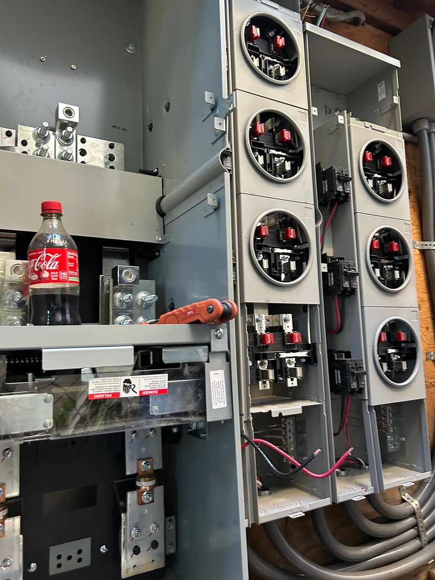 Electrical panel with six cooling fans, wiring, and a red soda bottle on a shelf