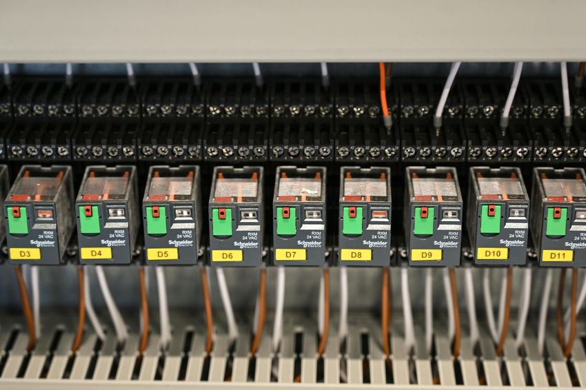 Row of electrical relays in a control panel with labeled switches and wiring.
