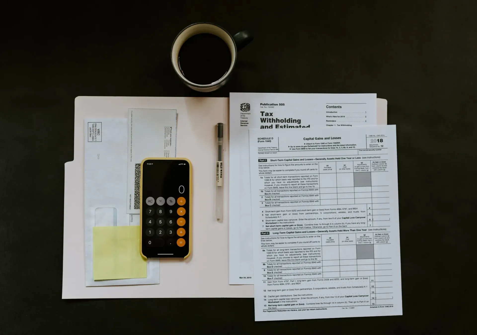 Desk with papers, a calculator, and a pen beside a tape roll and a receipt.
