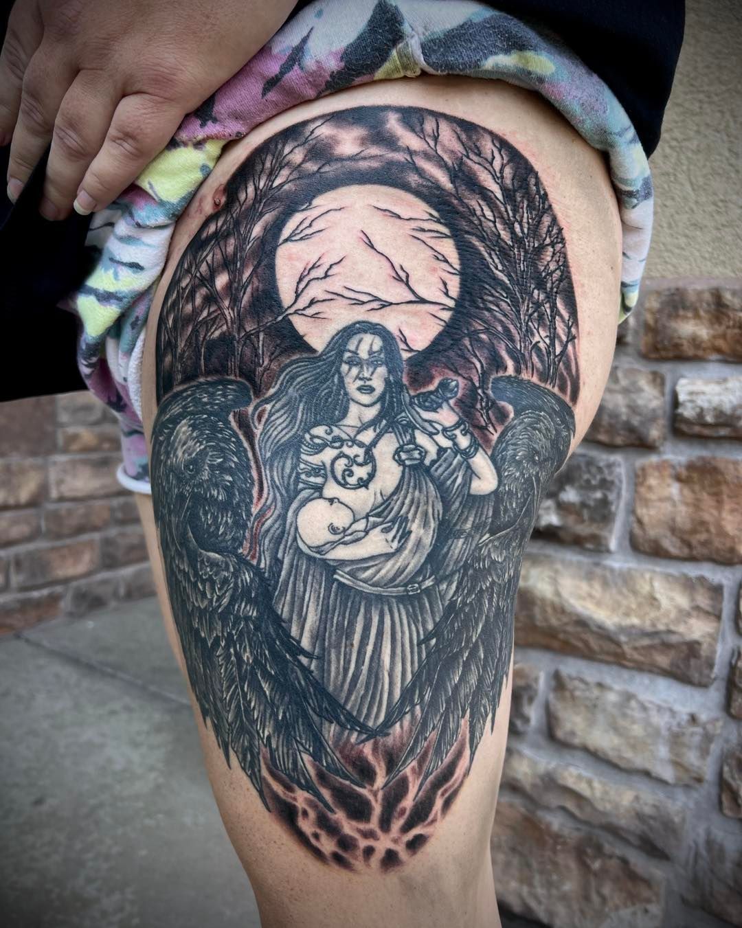 A woman has a tattoo on her leg of a woman holding a baby