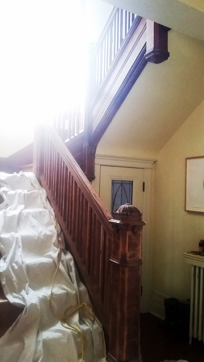 Un escalier en bois dans une maison avec le soleil qui brille à travers la fenêtre.