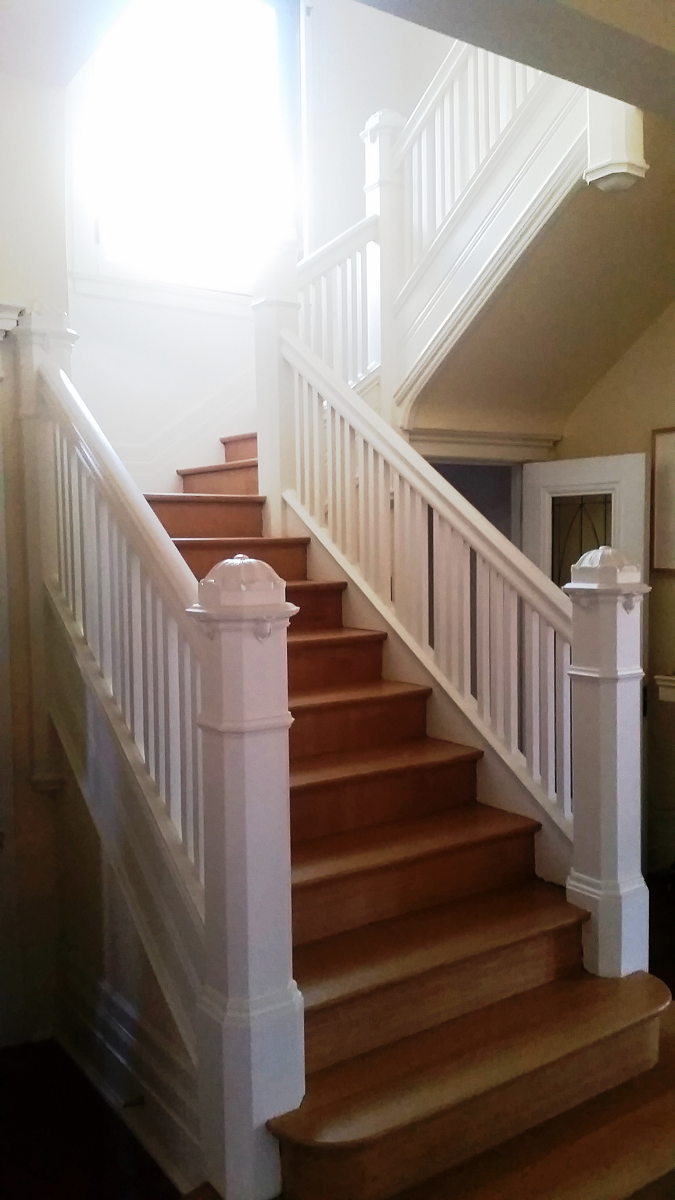 Un escalier avec une balustrade blanche et des marches en bois dans une maison.
