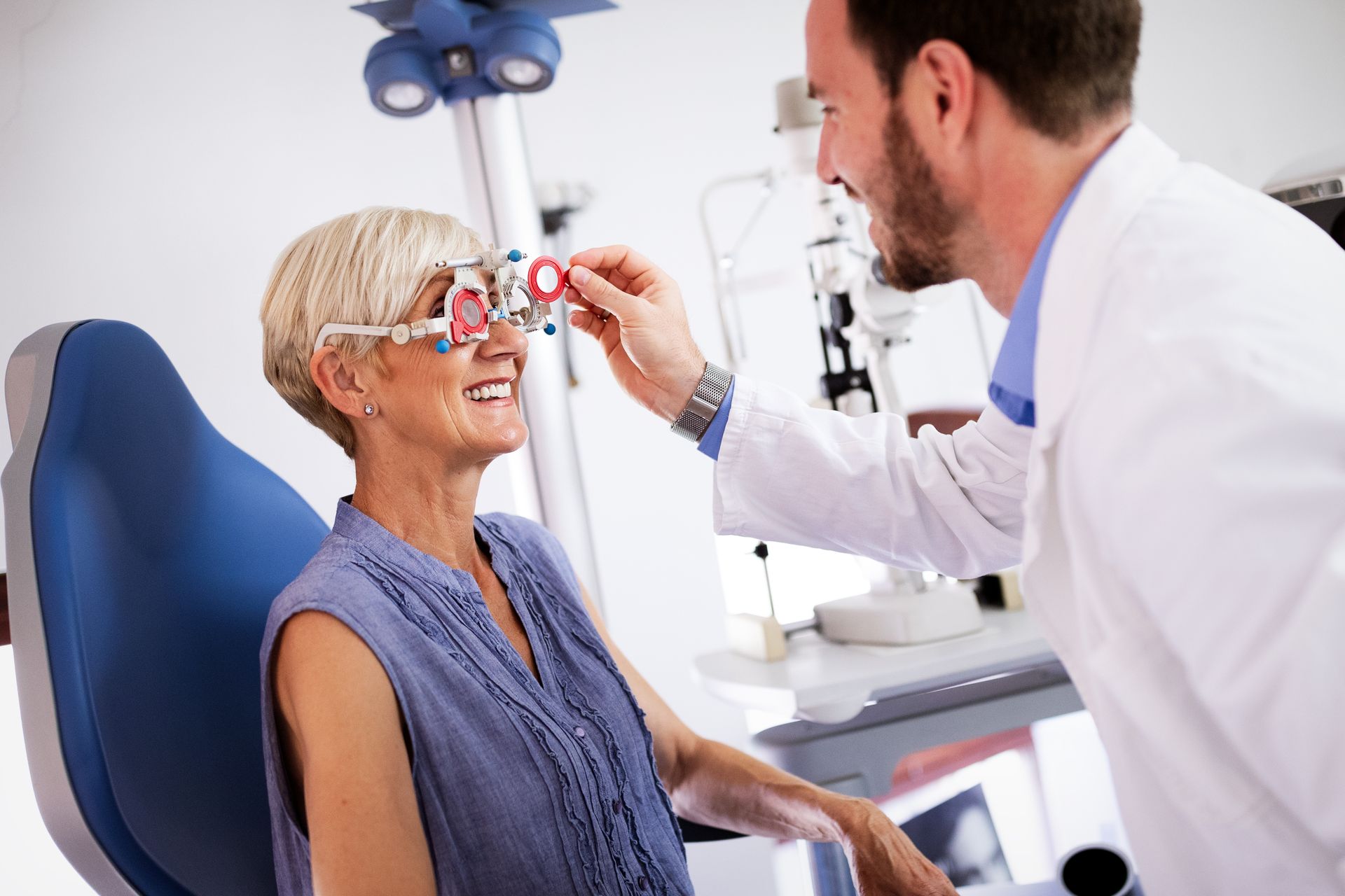 An eye doctor adjusting a phoropter during a patient's vision exam in a clinic. An eye doctor adjusting a phoropter during a patient's vision exam in a clinic.