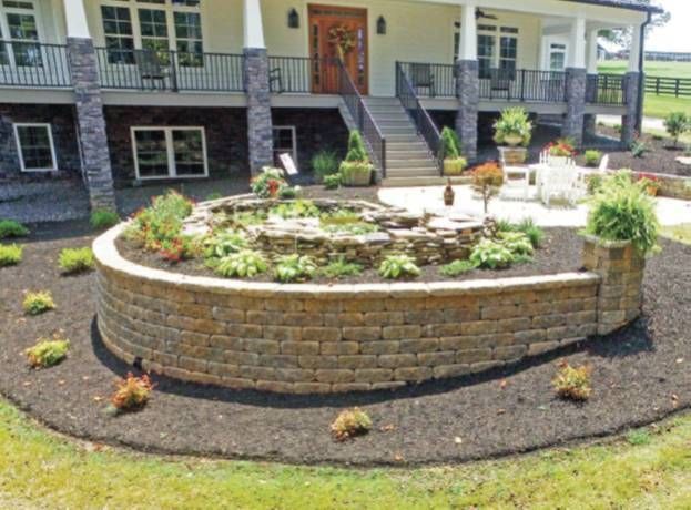 Raised circular stone garden bed in a landscaped yard outside a house
