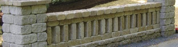 Stone garden retaining wall with a row of narrow decorative columns