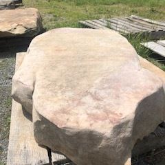 Large beige stone slab on a wooden pallet outdoors on grass
