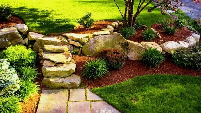 Stone steps and rocks in a landscaped garden with green grass and shrubs