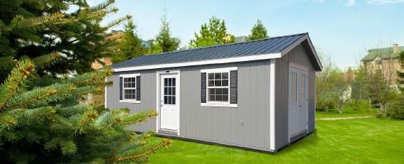 Gray shed-style garden office with white trim and solar panels on a grassy lawn