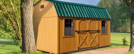 Small wooden garden shed with a green metal roof beside a tree in a sunny yard