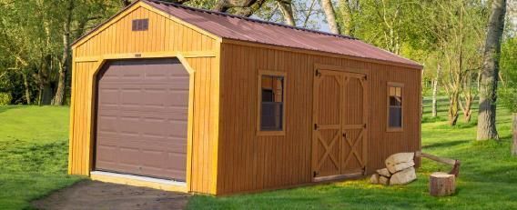 Wooden shed with brown garage door and side barn doors in a grassy yard with trees