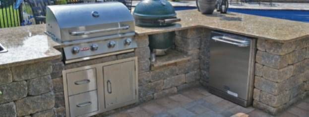 Outdoor stone patio with stainless steel grill and sink built into a stone counter