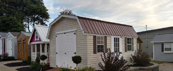 Small beige house with white trim and a metal roof, seen in a residential area at dusk.