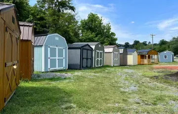 Row of colorful storage sheds along a grassy dirt path under a blue sky