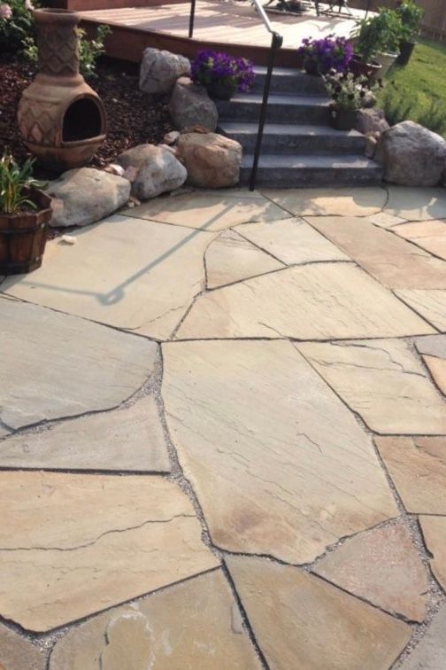 Stone patio with irregular flagstones, potted plants, and steps leading to a garden area