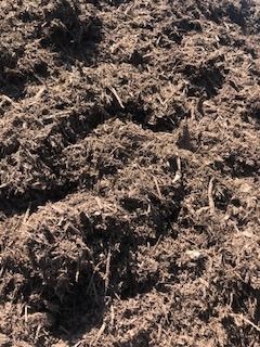 Close-up of dark brown mulch or soil with rough, fibrous texture