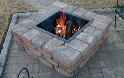 Stone fire pit with a burning fire in an outdoor patio area