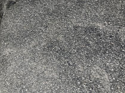 Close-up of rough gray gravel or asphalt surface with scattered small stones