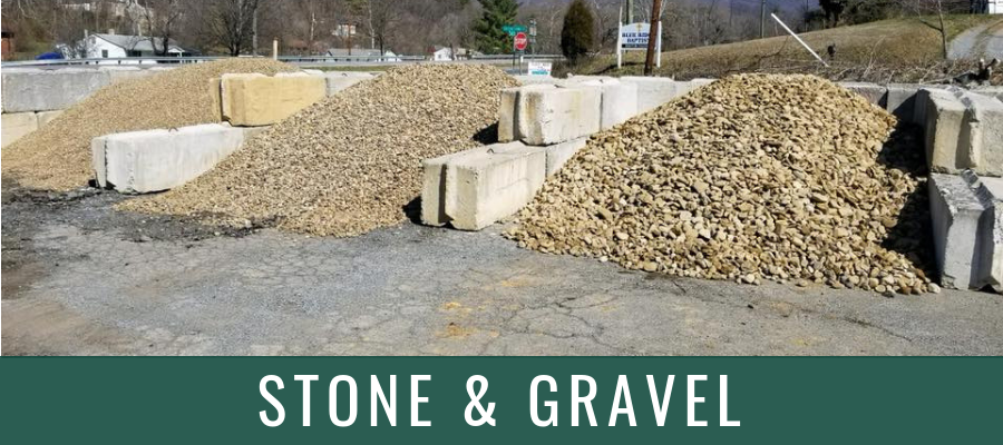 Piles of stone and gravel at an outdoor supply yard with a “STONE & GRAVEL” sign.