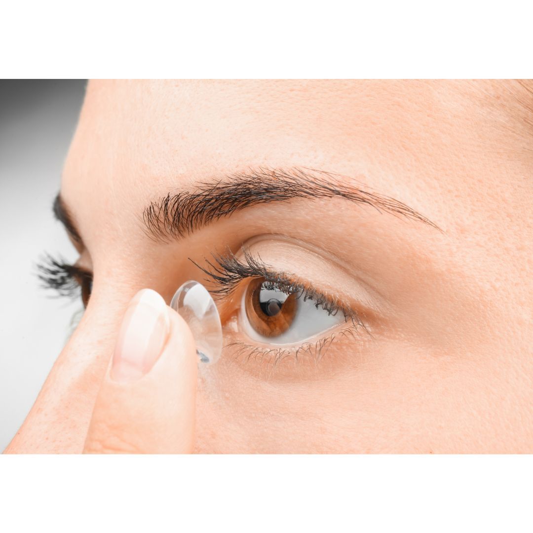 A woman is putting a contact lens in her eye.