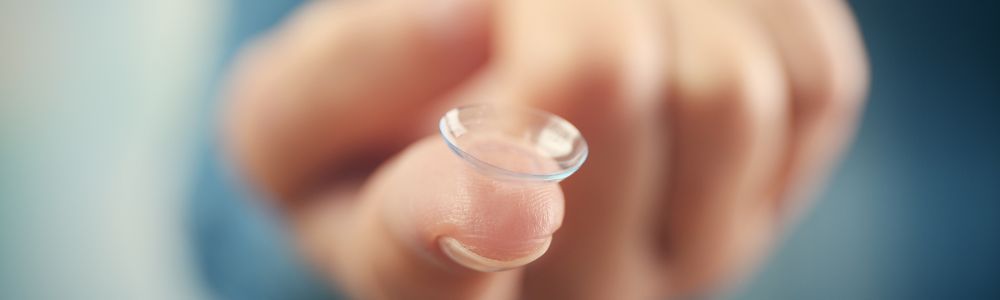 A person is putting a contact lens on their finger.