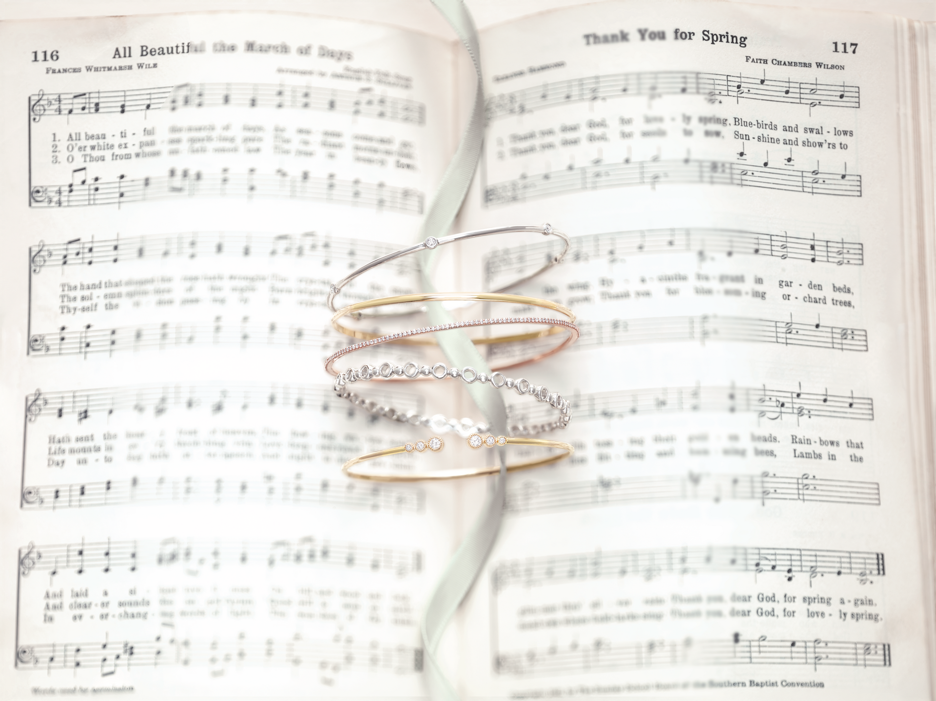A couple of bracelets are sitting on top of a sheet of music.